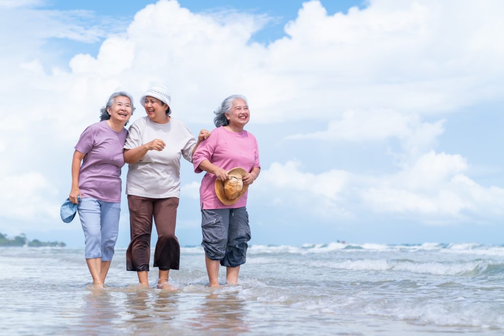 três idosas andando na praia